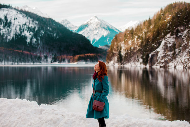 年轻的红发女孩穿着外套在阿尔卑斯山湖边图片下载
