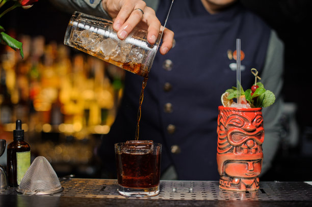 调酒师将新鲜和冰冷的酒精鸡尾酒倒入玻璃杯素材图片