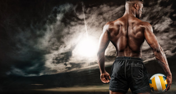 非裔美国运动员的肖像，沙滩排球运动员与一个球在日落。穿着运动服拿着球的年轻人。图片下载