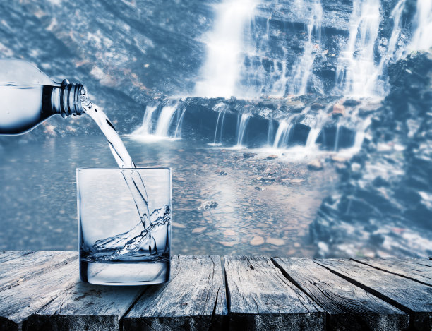 水靠瀑布从瓶子流进圆玻璃杯图片下载