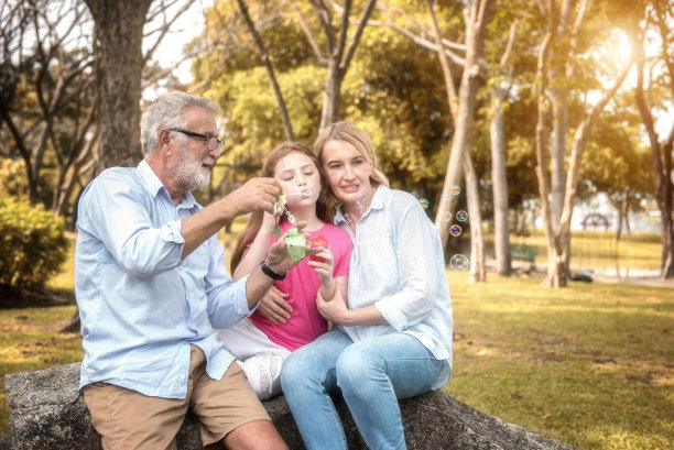 家人和女儿在花园里吹肥皂泡。软焦点的概念。图片下载