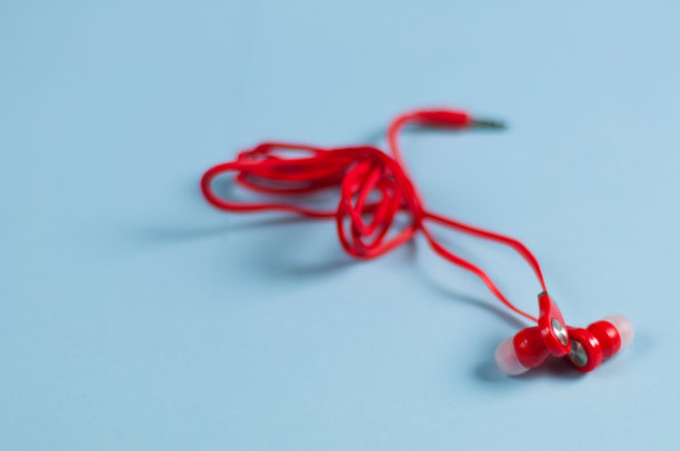 红色新耳机线和金属插头在蓝色纸背景图片下载