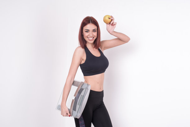 拿着体重秤和苹果的健康年轻女子图片下载