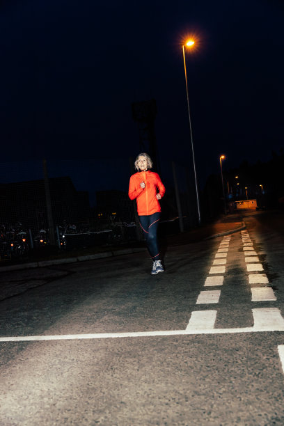 夜晚在城市街道上跑步的年长女人图片下载