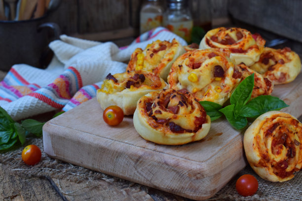 小披萨配马苏里拉芝士，火腿，罗勒，樱桃番茄。面包的酵母面团在木制的背景。迷你披萨。自制烘焙。图片下载