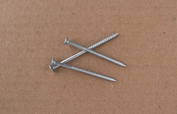 纸板背景上的长金属架子螺钉。图片下载