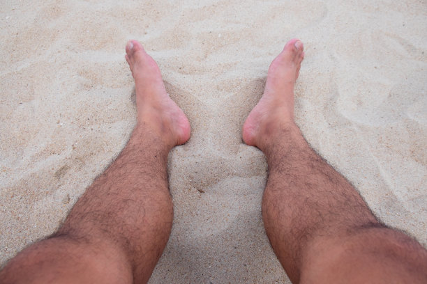 近距离观察躺在沙滩上的人类双腿，旅行概念图片下载