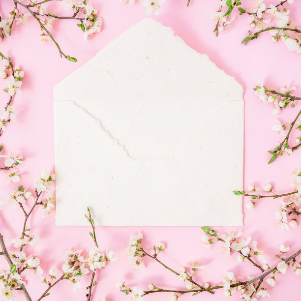 框架与春天的鲜花和白色纸质复古信封在粉红色的背景。平躺，俯视图。图片下载