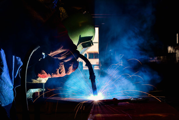 工业焊工在工厂中焊接装配式建筑，焊接过程采用助熔剂芯焊，FCAW图片下载