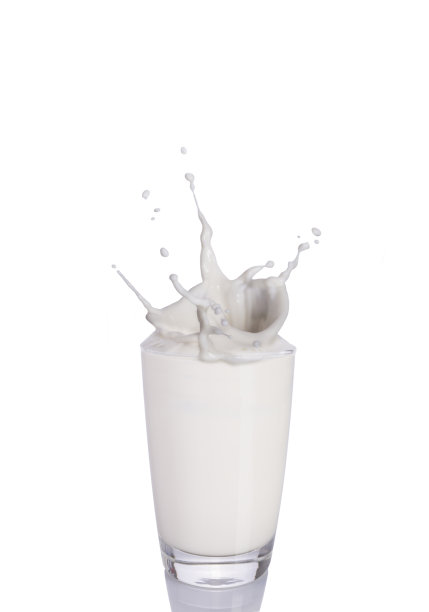 玻璃杯里洒了一点牛奶。特写镜头图片下载