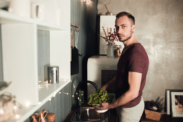 厨房里的男人。烹饪时间。乡村色彩的生活方式照片。人与健康的饮食观念。穿着运动服的家伙在厨房里洗沙拉图片下载