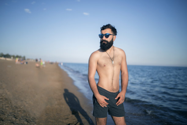 那个戴眼镜的年轻人正在海滩上拍照。图片下载