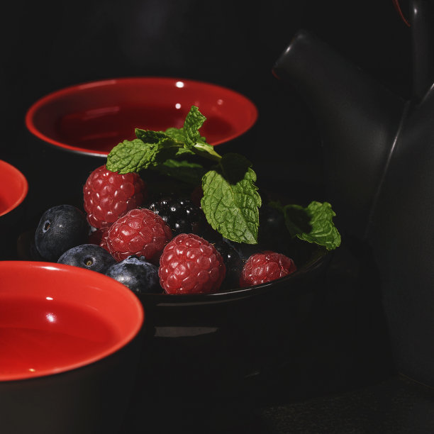 茶桌上的茶具：带有黑红色浆果的黑色和红色杯子素材图片