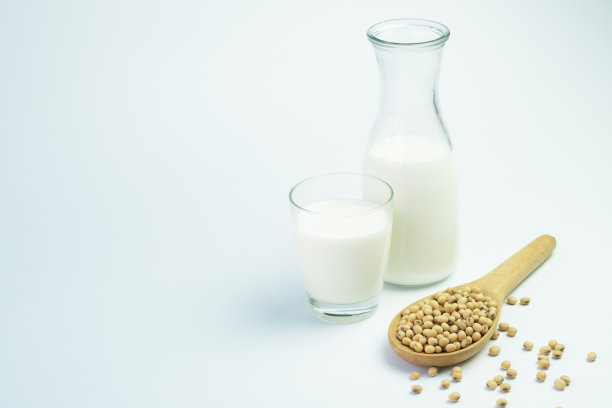 玻璃里的豆浆和白色背景上的大豆。图片下载