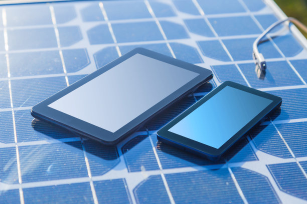 用太阳能板给手机充电。素材图片