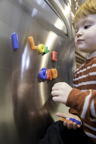 可爱的小男孩在玩冰箱上的磁铁文字，我爱爸爸图片下载