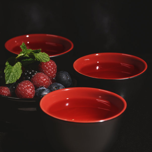 茶桌上的茶具：带有黑红色浆果的黑色和红色杯子素材图片