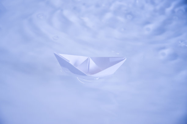 在清澈的蓝色和绿松石色的水中折叠的小纸船图片下载