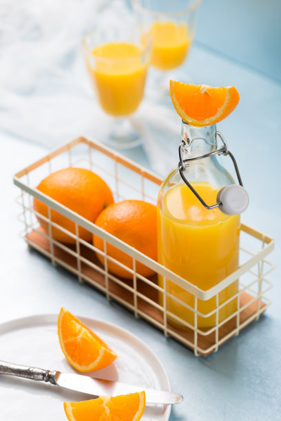 新鲜橙汁饮料在瓶子与橙色水果在蓝色背景图片下载