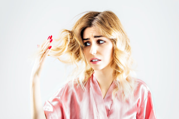 迷人的女人惊恐地看着分叉的发梢素材图片
