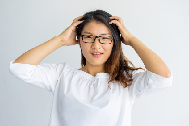 困惑的年轻亚洲女子按摩头部，看着镜头素材图片