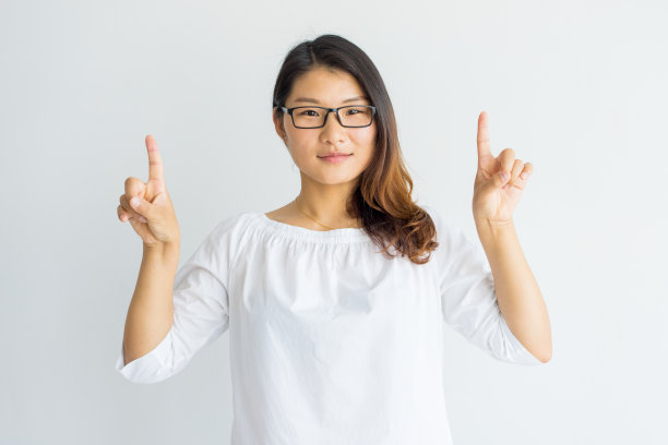 指着上面的留着挑染发的表情严肃的聪明的亚洲女孩素材图片