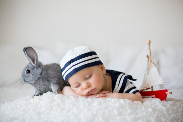 可爱的小男孩，穿着水手服，睡在木船和可爱的小兔子图片下载