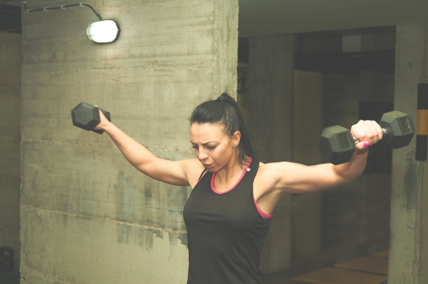 美丽年轻有魅力的女孩哑铃锻炼肩部肌肉，真人训练没有姿势，力量和条件概念图片下载