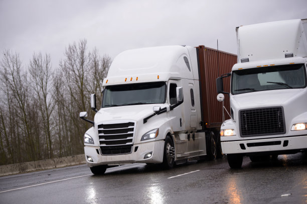 两辆大卡车和半挂车在雨中并排行驶图片下载