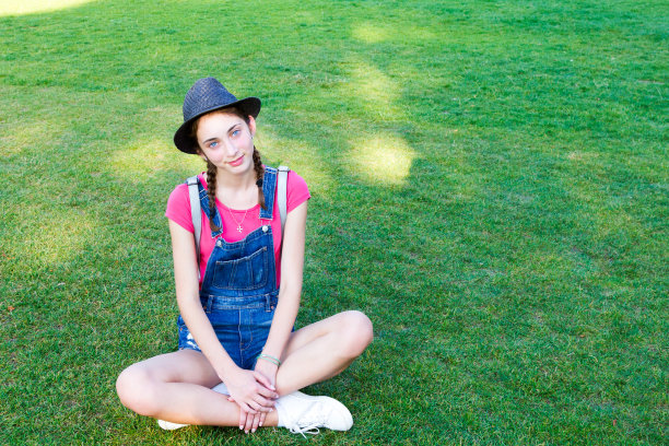 女孩坐在绿色的草地上图片下载