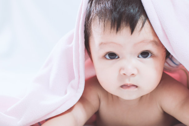 在粉红色毯子上微笑的可爱亚洲女婴素材图片