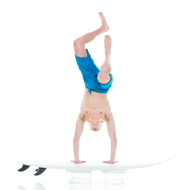 英俊的年轻人冲浪和做倒立图片下载