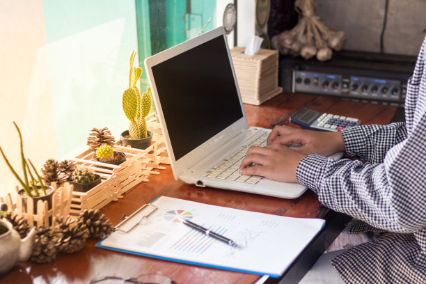 关闭使用电脑在咖啡店工作的女商人。图片下载