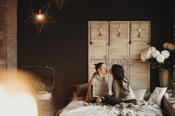 一对夫妇躺在舒适的房间里的床上接吻。图片下载