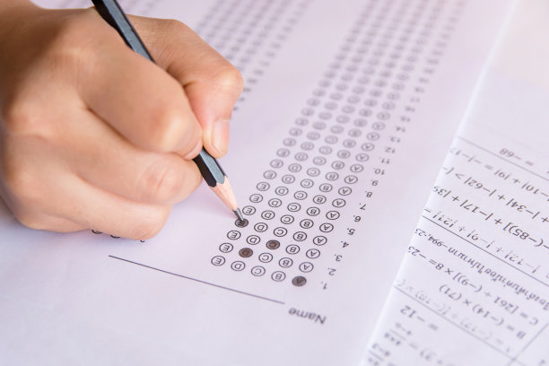 学生手持铅笔在答题纸和数学问题纸上写下选定的选项。学生考试做考试。学校考试图片下载