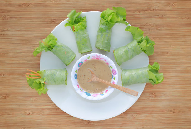 新鲜蔬菜沙拉卷在面条管与芝麻酱碟在白色背景。图片下载