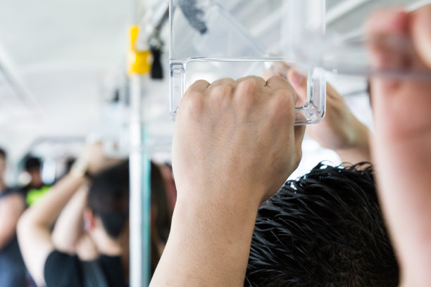 在拥挤的公共交通工具上，乘客紧握着扶手。图片下载