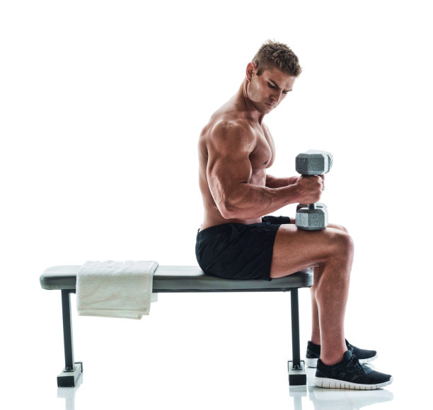 肌肉发达的帅哥在健身长椅上举着哑铃图片下载