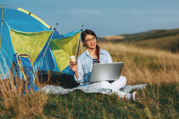 一个年轻女子在营地使用笔记本电脑图片下载
