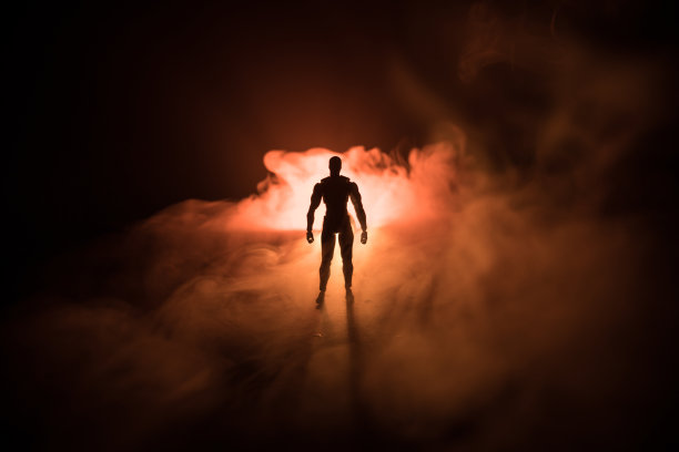 一个人的剪影站在黑暗的雾色调的背景。用灯光装饰的男士照片放在桌子上。图片下载