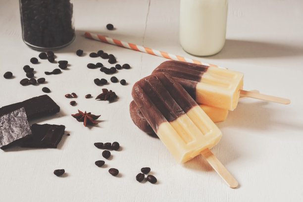 两种颜色的冰淇淋在一根棍子上，米黄色在一张白色的桌子上。咖啡香草冰淇淋，调色照片。图片下载