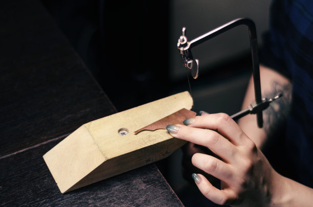 女主人在家庭作坊工作。用于珠宝的锯。国内生产。艺术色彩校正，选择性聚焦图片下载