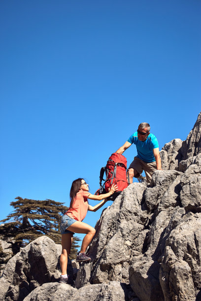 一个女孩的帮助之手在登山。图片下载