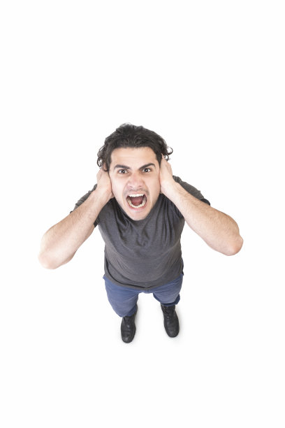 在白色背景下，一名愤怒的年轻人一边看着摄像机一边用手捂着耳朵痛苦地尖叫图片下载