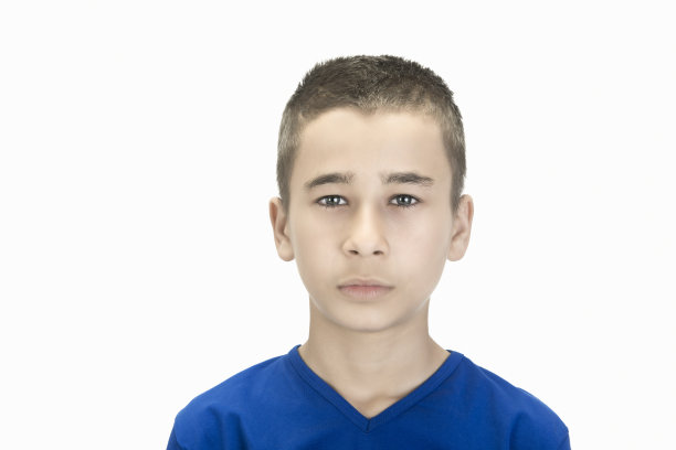近距离肖像放松小男孩看着相机与空白的面部表情在一个白色的背景图片下载
