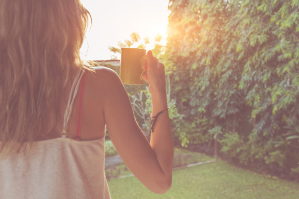 可爱的女孩在门廊上享受早上的咖啡。素材图片