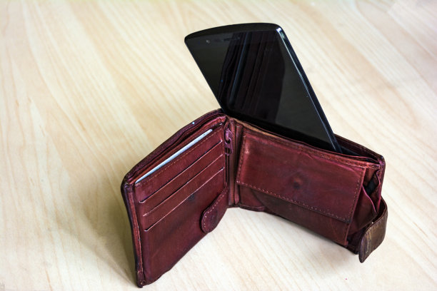 用智能手机支付-移动支付的概念，手机里面代替了纸币。特写捕捉，选择性聚焦。图片下载