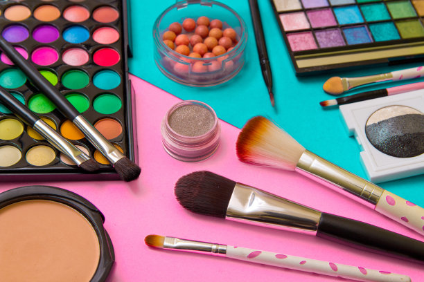 用粉色和绿松石色的几何背景作为眼影和口红的笔刷。用于专业化妆的装饰性化妆品。眼影颜色的趋势。图片下载