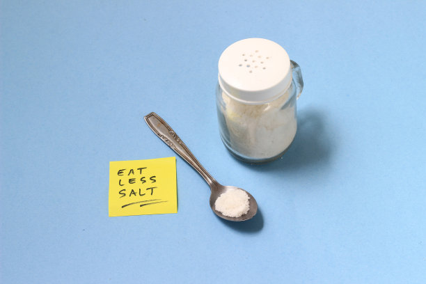 健康生活方式插画：茶匙中的盐，摇壶，带有“少吃盐”字样的黄色便签，蓝色背景图片下载