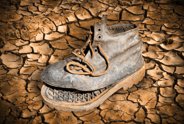 破旧的靴子被丢弃在破碎的地面上——贫穷的概念图片下载